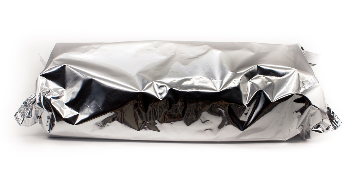 A crumpled aluminum foil package is wrapped tightly around a food item, showing proper storage techniques.