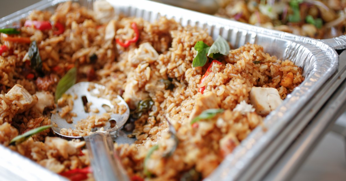 The Advantages of Aluminum Foil for Oven-Ready Meals Seasoned fried rice with chicken, red peppers, and fresh herbs served in a large aluminum foil catering tray with a spoon.