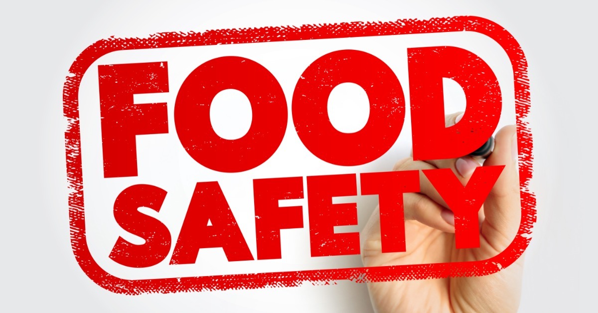 A hand holds a red marker and writes Food Safety inside a red stamp-style rectangle on a white background. A hand holds a red marker and writes Food Safety inside a red stamp-style rectangle on a white background.