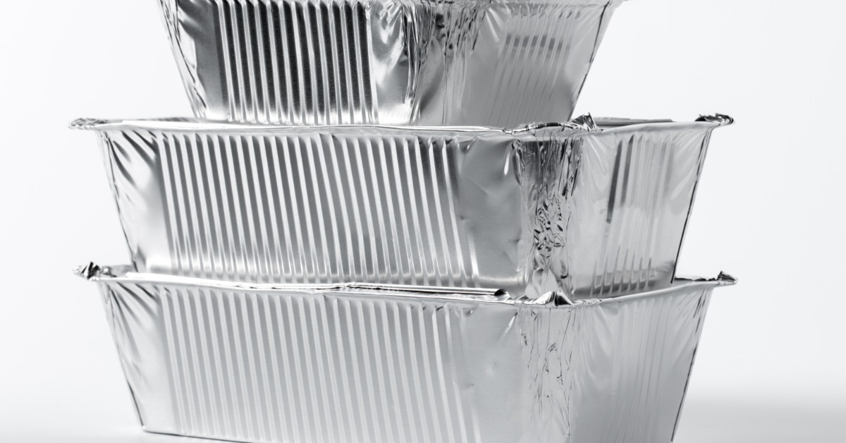A side view of three rectangular aluminum foil food containers in various sizes stacked on top of one another.