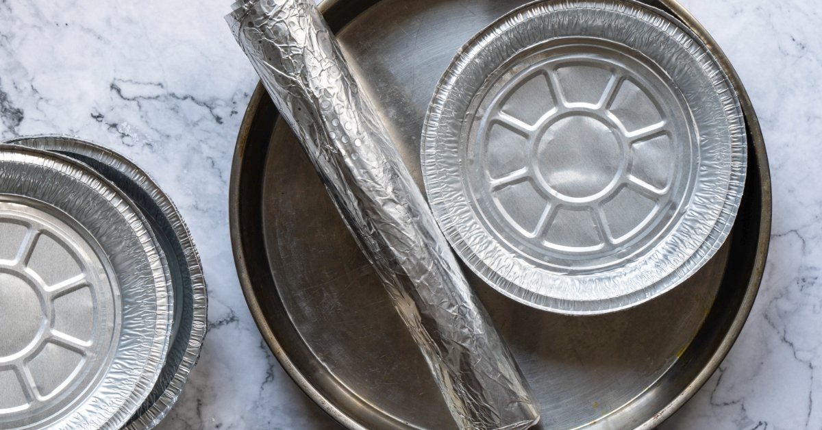 An overhead close-up of various types of aluminum for cooking and baking, including foil rolls and round baking pans.