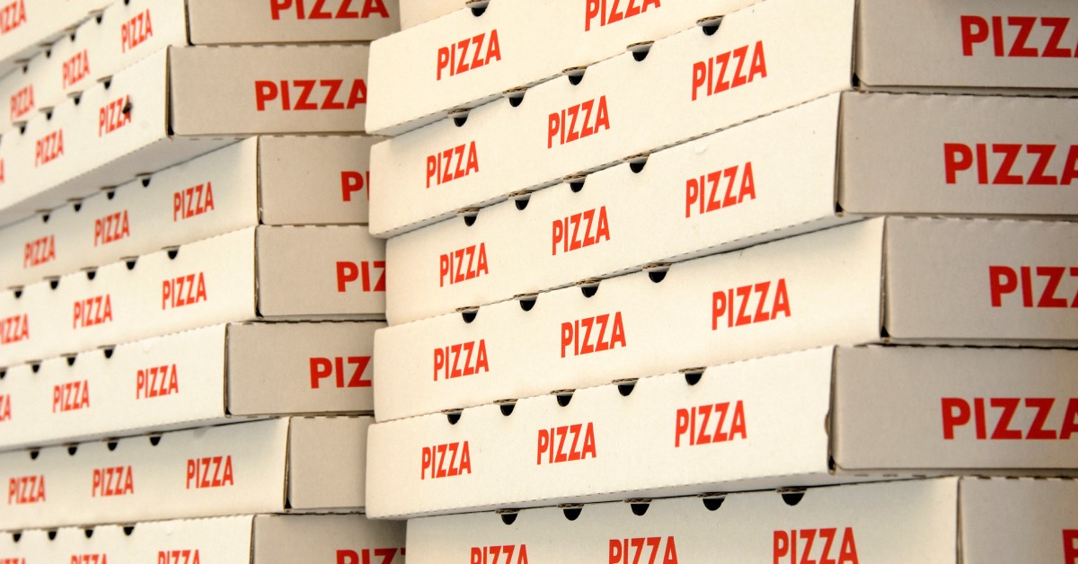 Two large stacks of white cardboard pizza boxes are labeled with the word "pizza" in red along the sides.