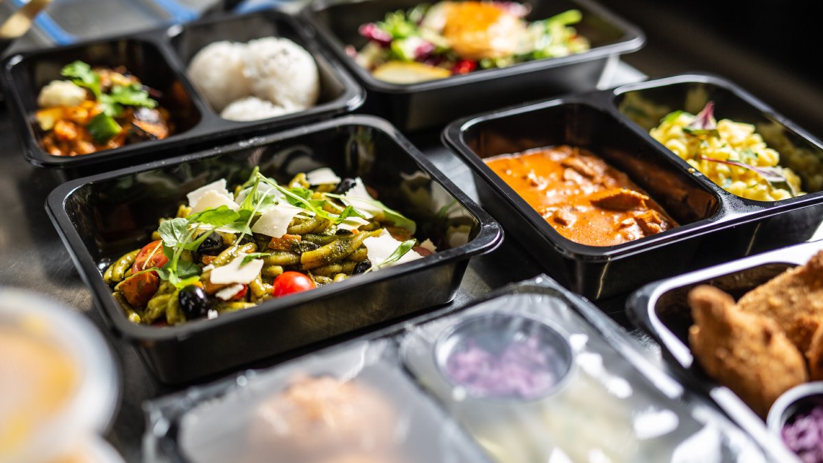 Open and closed plastic disposable takeaway containers with various meals ready for delivery from the restaurant.