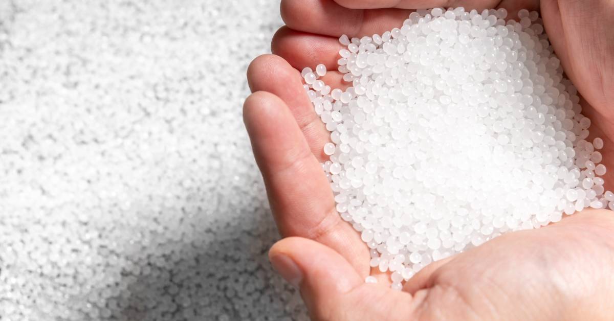 An engineer holding hundreds of white PET plastic polymer pellets before melding them for molding into shape.