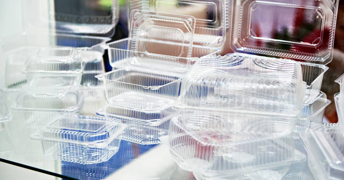 Multiple stacks of clear plastic disposable food containers set out on a restaurant counter for delivery and take-out.