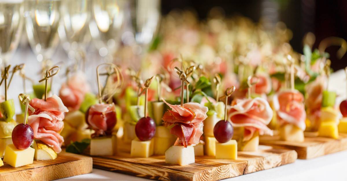 A few wooden boards filled with charcuterie-style snacks—cheese, fruit, and meat skewered on toothpicks.