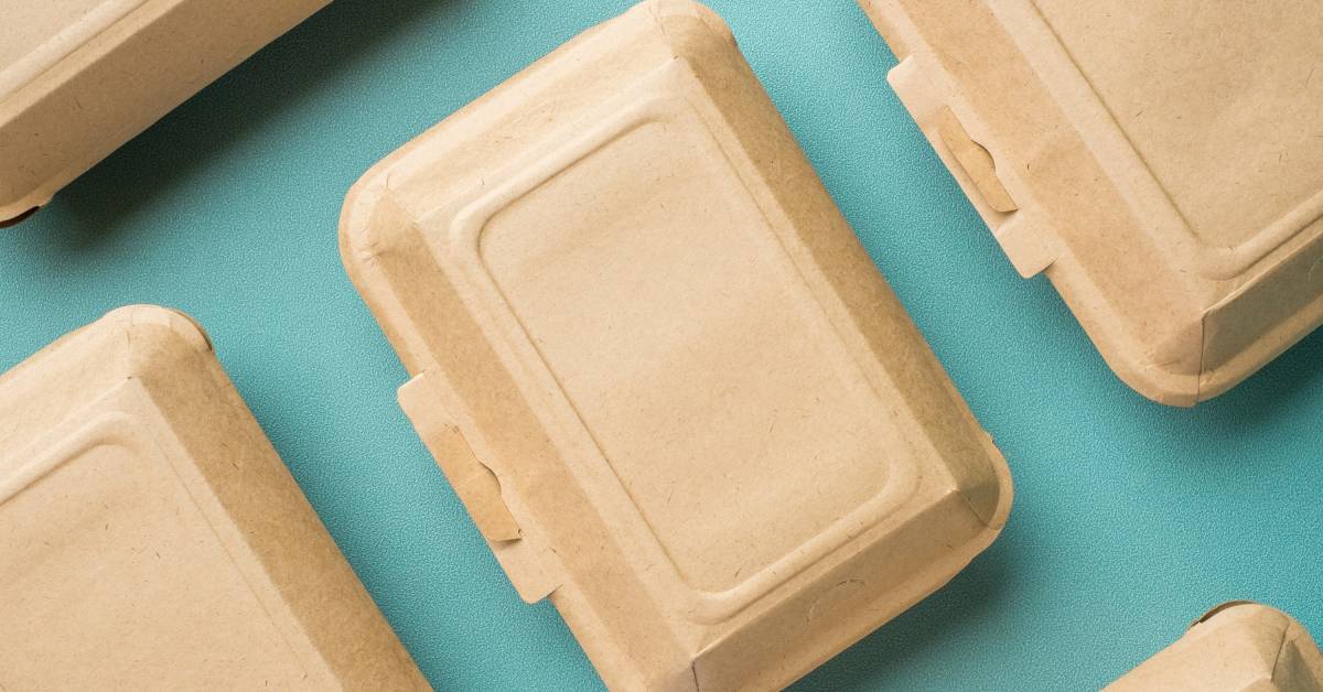 Rectangular brown disposable food containers are neatly arranged on a teal surface, highlighting an eco-friendly choice for takeout packaging.