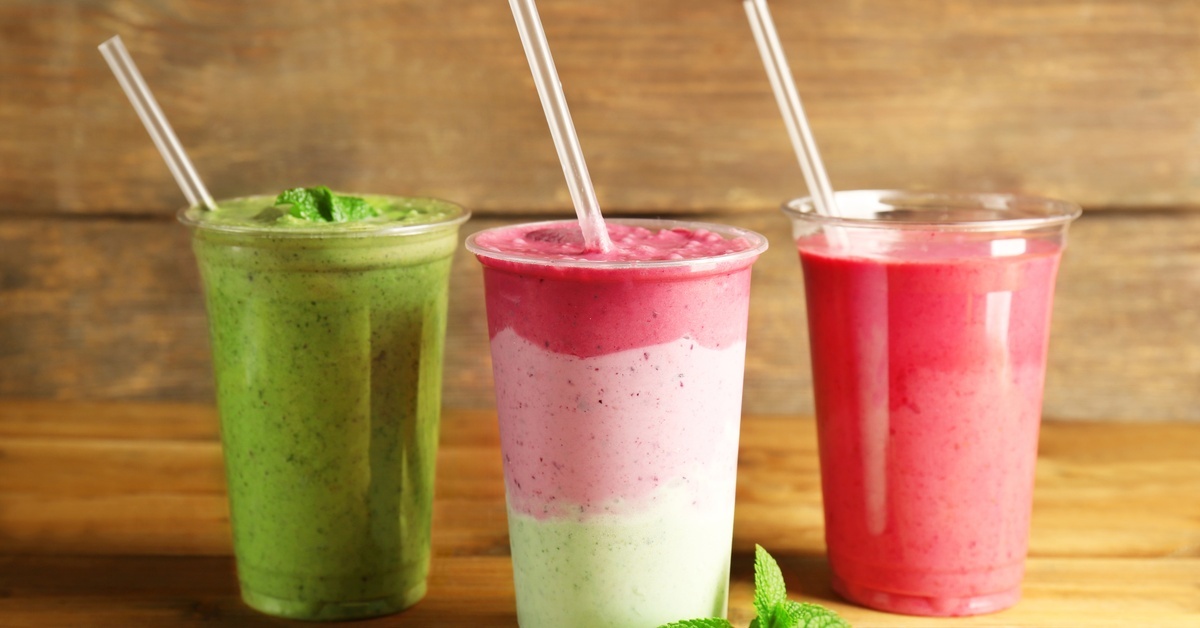 A trio of fruit smoothies—the left and right smoothies are green and pink, and the smoothie in the middle is green, pink and, red.