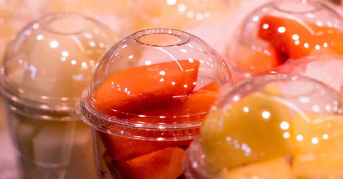Several PET cups hold fruit salads. Some have pieces of orange papaya, while another one features pineapple. Several PET cups hold fruit salads. Some have pieces of orange papaya, while another one features pineapple.