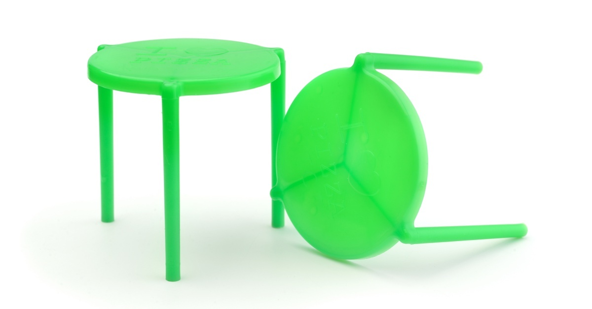 Two green plastic pizza savers sit side by side. One sits on its legs, while the other sits on its side.