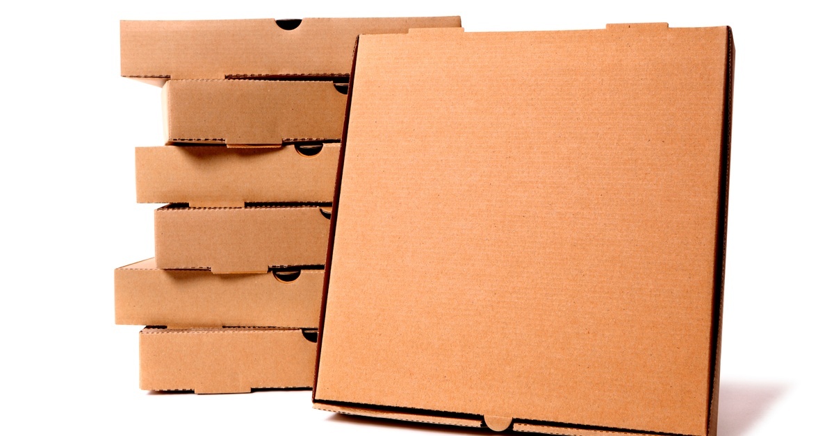 Stacked brown pizza boxes are in front of a white background. One box is upright and leans against the stack.